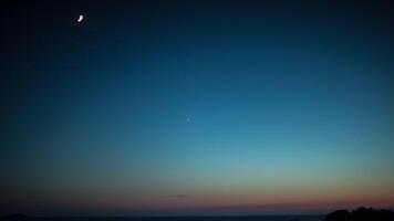 The moon and venus are seen in the sky over the ocean video
