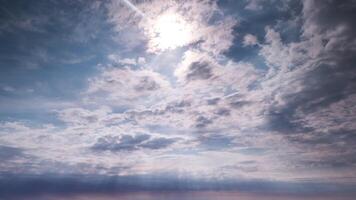 A man is standing on a beach with a sun shining through the clouds video