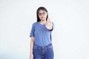 Beautiful Asian woman holds her open palm forward in a rejection gesture against a plain white background photo