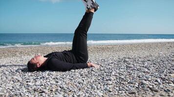 Boy Does Lower Abs With Legs Exercises On The Beach Near The Sea video