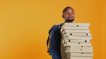 Clumsy deliveryman dropping a huge stack of pizza boxes in studio, wasting a lot of food and making a mess. Young distressed man makes a mistake and spills a large pile of fast food. Camera B. video