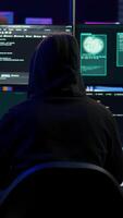 vertical com experiência hacker escrevendo linhas do código em computador a partir de subterrâneo bunker, amarrar para pegue passado segurança sistemas. Vampiro programador construção scripts este pode hackear dispositivos, Câmera b video