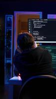 vertical perigoso hacker escrevendo linhas do código em pc a partir de segredo apartamento, tentando para pegue passado segurança sistemas. mal Programas desenvolvedor construção scripts este pode hackear dispositivos, Câmera b video