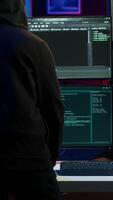 Vertical Hacker arriving in hidden underground shelter with laptop, prepared to launch malware attack on websites. Scammer in apartment starting work on dangerous script that can breach security, camera A video