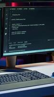 vertical fechar acima tiro do perigoso hacking código corrida em Alto tecnologia computador sistema monitores. programação scripts mostrando em pc monitores dentro esvaziar Criminoso esconderijo usava de hackers para comprometer ilegal Atividades video