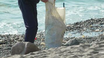 Garbage on beach - Elder Man collects garbage on beach after storm, maintaining cleanliness and preserving environment. video