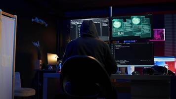 Cybercriminal fraudulently breaching security systems while hiding in secret HQ. Hacker breaking down security systems defenses using rogue scripts to steal valuable data, camera B video