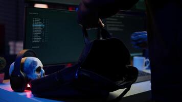 Hacker taking laptop out of suitcase, prepared to launch DDoS attack. Cybercriminal entering apartment, getting notebook from bag, starting work on malware script, close up, camera B video