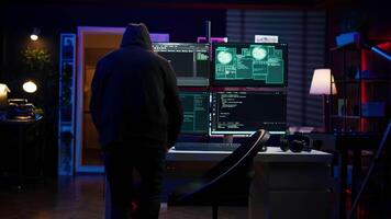 Hacker arriving in secret base with laptop, ready to start programming viruses. Scammer in criminal den opening notebook to exploit network servers and bypass security measures, camera B video