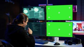 Scammer hacking using green screen PC and getting critical error notification while trying to infiltrate banking systems. Hacker runs script on chroma key display, failing to breach firewall, camera B video
