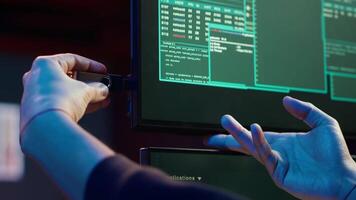 Hacker doing illegal activities in secret underground base, uploading USB flash drive containing data obtained from victim after tricking it into installing ransomware program, camera A video