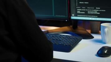 Dangerous man hacking, stealing credit card numbers and infiltrating banking systems, handheld camera shot. Close up of hacker running code in apartment on PC monitors, camera A video