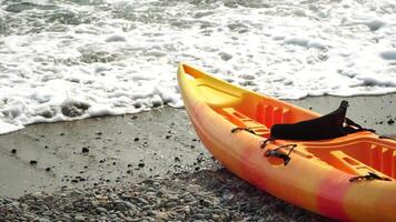 Kayak, Beach, Water - Colorful kayaks on sandy shore with glistening water backdrop on sunny day inviting exploration. Summer holiday vacation and travel concept video