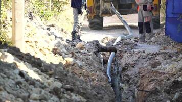 Plastic pipes laid in trenches. Workers are installing water pipeline under a city street in a trench. New pipeline in a process of building, under construction. Workers are laying pipeline. Close up video