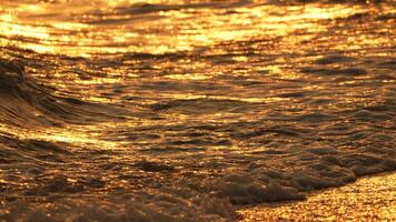 Abstract Blurred golden sea at sunset. Sun reflects and sparkles on waves with bokeh, illuminating warm sea. Summer ocean nature backdrop. Holiday, vacation and recreation. Weather and climate change video