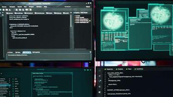 Close up of code running on computer displays in empty apartment used by hacker stealing secrets. Illegal scripts on PC screens used by spy infiltrating governments, handheld camera shot video