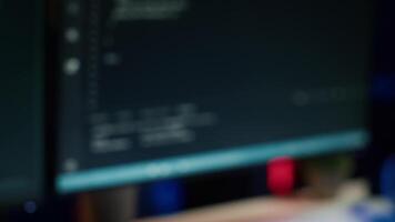 Extreme close up of software interface on PC screens showing lines of code running in empty criminals den. Hacking malware programming script on displays in underground base, handheld camera shot video