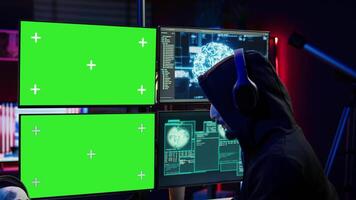 Hacker using isolated screen monitor and artificial intelligence to write spyware software, listening music. Scammer wearing headphones using AI and chroma key PC to do fraud using AI, camera B video