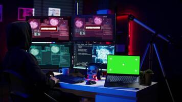 Hacker using isolated screen laptop and AI technology to deploy malware on unsecured devices. Scammer stealing sensitive data from unaware users using mockup notebook, camera B video