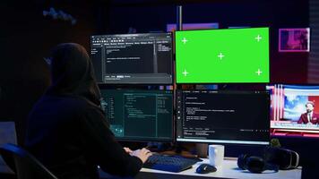 Dangerous man hacking using green screen PC, stealing credit card numbers and infiltrating banking systems. Hacker running code in apartment on mockup computer display, camera B video