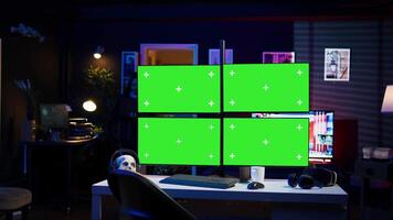 Hacker using isolated screen multi monitor PC setup, doing computer sabotage using ransomware. Cybercriminal walking with laptop, breaching firewalls in apartment with mockup displays, camera B video