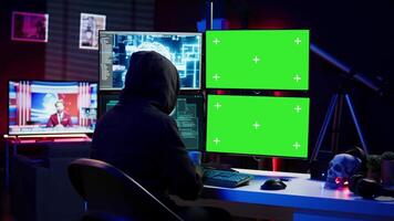 Rogue computer scientist uses AI deep learning and green screen PC to develop malware. Hacker uses artificial intelligence neural networks and chroma key monitors to build script, camera B video