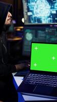 vertical isolado tela computador portátil usava de cibercriminoso dentro subterrâneo esconderijo para escrever linhas do código e malware scripts. brincar caderno usava de mal programador dentro escondido bunker, fechar acima tomada, Câmera b video