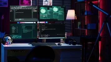 Panning shot of high tech computer system running malicious code in empty apartment. PC monitors in empty neon lit criminal hideout used by hackers to commit illegal activities video