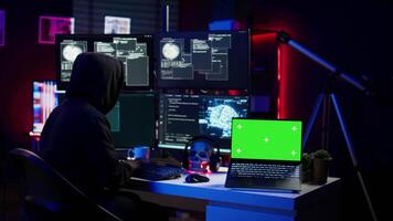Green screen laptop used by hacker in underground hideout to write lines of code, developing virus that get past security systems. Chroma key device used by evil developer in hidden bunker, camera B video