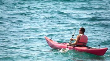 Man kayak Sea. Strong athletic man learns to paddle kayak in open sea ocean on sunny day. Summer holiday vacation and travel concept. Aerial view. Slow motion video