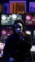 vertical mal programador dissimulação identidade usando Móvel telefone para filme resgate dentro segredo base. scammer com anônimo mascarar usando celular para registro chantagem imagens de vídeo, ameaçador vítimas, Câmera b video