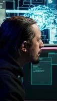 Vertical Hacker using artificial intelligence technology to write spyware software able to gather information from users. Scammer in apartment doing fraud using AI, close up, camera A video