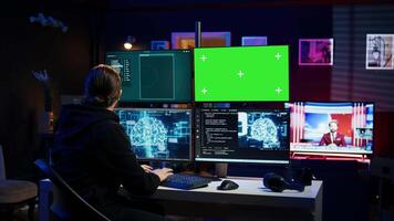 Hacker using green screen monitor and artificial intelligence to write spyware software gathering data from users. Scammer in apartment using AI and mockup PC display to do fraud using AI, camera B video