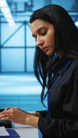 Vertical IT engineer looking at PC screen, working in network security data center, ensuring optimal performance. Woman monitoring energy consumption across operational server rigs components, close up shot video