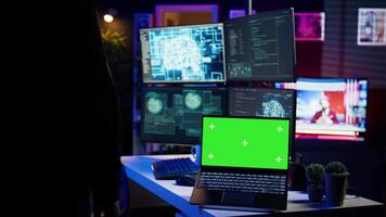 Hacker in hidden place using green screen laptop to deploy malware on unsecured devices, stealing sensitive data from unaware users online and selling it on black market, camera B video