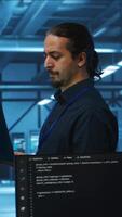 Vertical Manager overseeing server room, running code on laptop, troubleshooting and upgrading technologically advanced hardware clusters. System administrator programming in server farm video