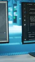 Vertical Computers in empty data center facility managing rackmounts energy consumption. Close up of script on PC monitors used for automation and monitoring processes in server room, camera A video