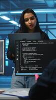 Vertical Portrait of smiling Indian manager in server room managing team of engineers looking for equipment misconfigurations. Happy team leader coordinating employees checking data center bottlenecks video