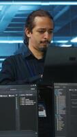 Vertical Portrait of smiling manager using laptop, supervising team in server hub providing computing resources for workloads. Happy team leader oversees engineers in data center mending supercomputers video