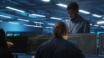 Supervisor in server hub workplace managing diverse team of developers looking for equipment software misconfigurations. Manager coordinating professionals mending data center bugs video