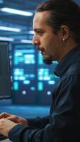 Vertical System administrator working in high tech server room capable of storing vast amounts of data, using computer. IT engineer typing on PC keyboard, upgrading servers controlling network resources video