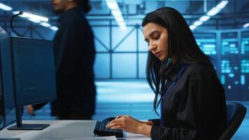 IT engineer looking at PC screen, working in network security data center, ensuring optimal performance. Woman monitoring energy consumption across operational server rigs components, close up shot video