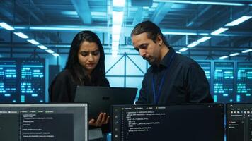 Technicians working in high tech server hub, analyzing data on laptop to ensure seamless data flow. Coworkers examining equipment in data center, ensuring system integrity and security video