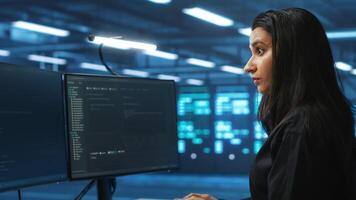 Meticulous engineer inspecting operational server rows in computer network security data center. Woman supervising supercomputers providing processing and memory resources for various workloads video