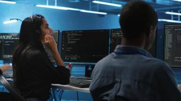 Woman talking in headphone mic, doing system analysis of server farm supercomputers. IT support worker in remote call using headset microphone in data center housing storage infrastructure video