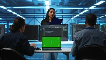 Isolated screen laptop in front of IT support workers coding on computers and talking with managers, upgrading equipment. Engineers at PC desk overseeing server clusters using chroma key notebook video