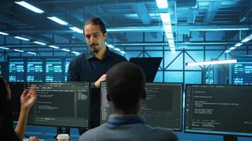Manager supervising multiethnic team working in data center ensuring optimal performance. Supervisor and employees monitoring energy consumption across server rigs components video
