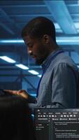 Vertical Engineer inputting data on tablet in server hub, monitoring data center energy consumption across hardware. Technician inspecting mainframes, ensuring malfunctions are repaired video