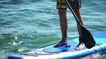 Man Sup Sea. Strong athletic man learns to paddle sup standing on board in open sea ocean on sunny day. Summer holiday vacation and travel concept. Aerial view. Slow motion video