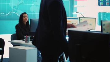 General director CEO sharing insight about a new development strategy with his employees, showing important data reports to analyze organizational activity status in a control room. Camera A. video